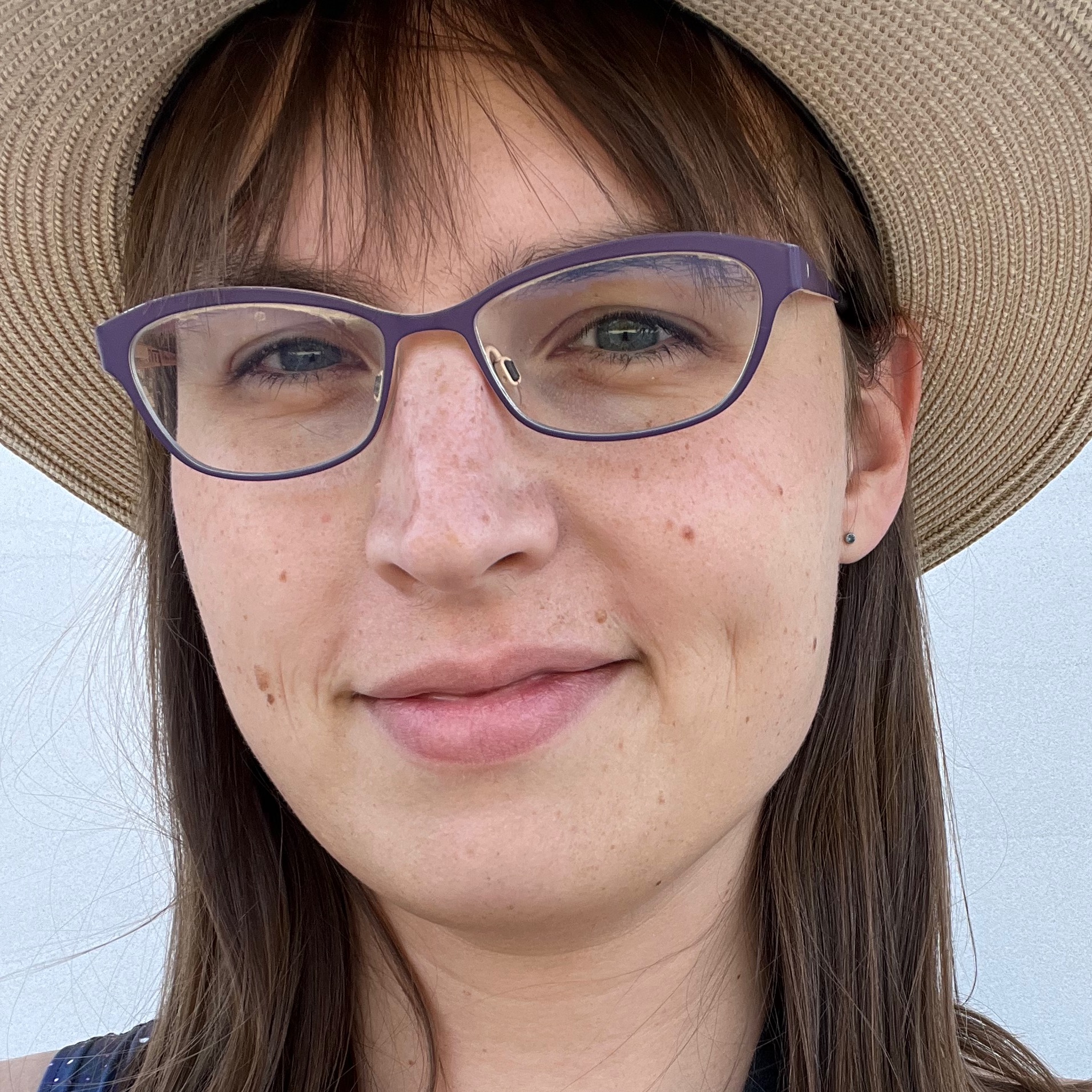  Me, wearing a hat and smiling slightly, standing in front of a stone background. 