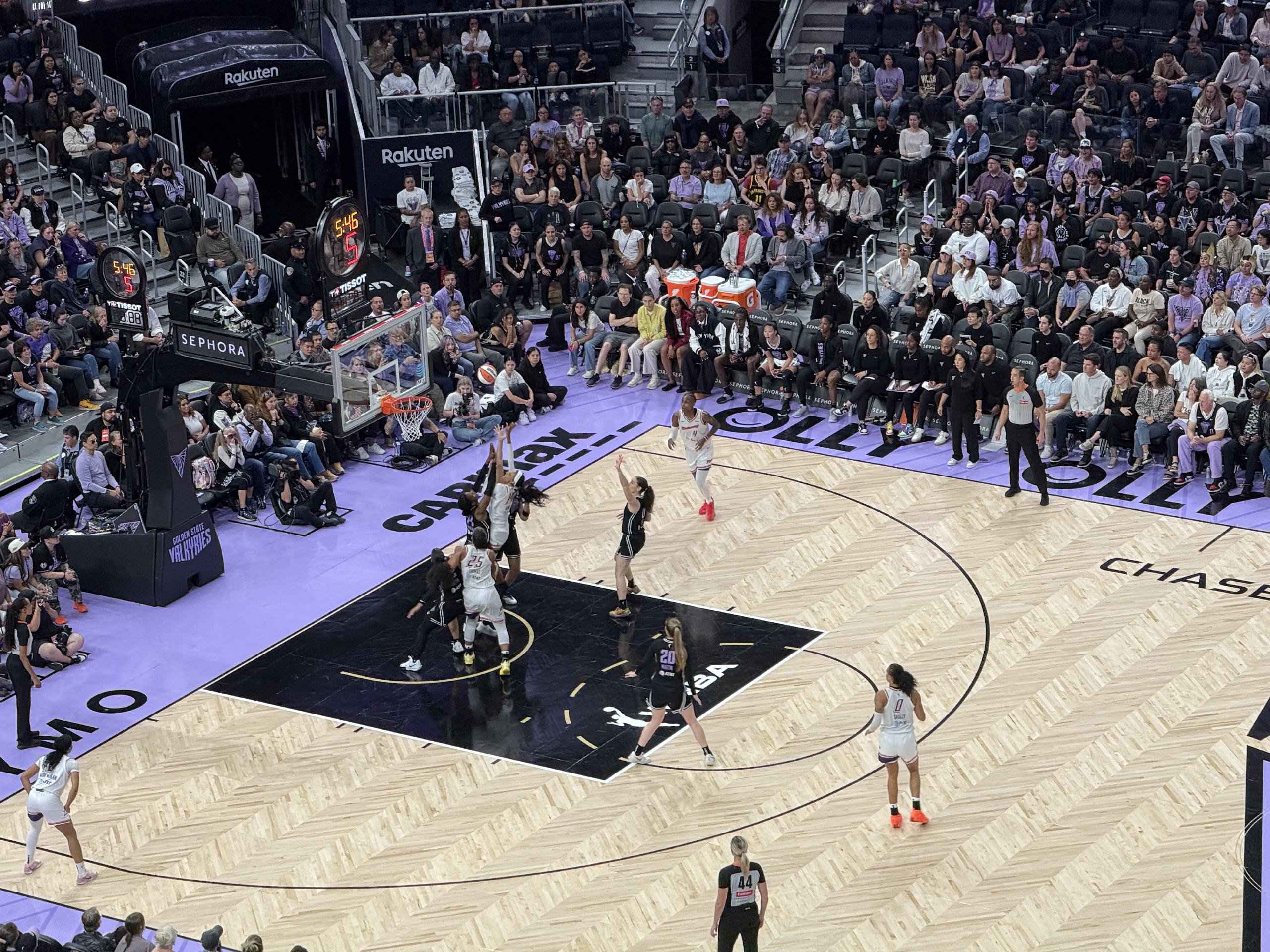 Several players reach for the ball as it flies toward the basket.
